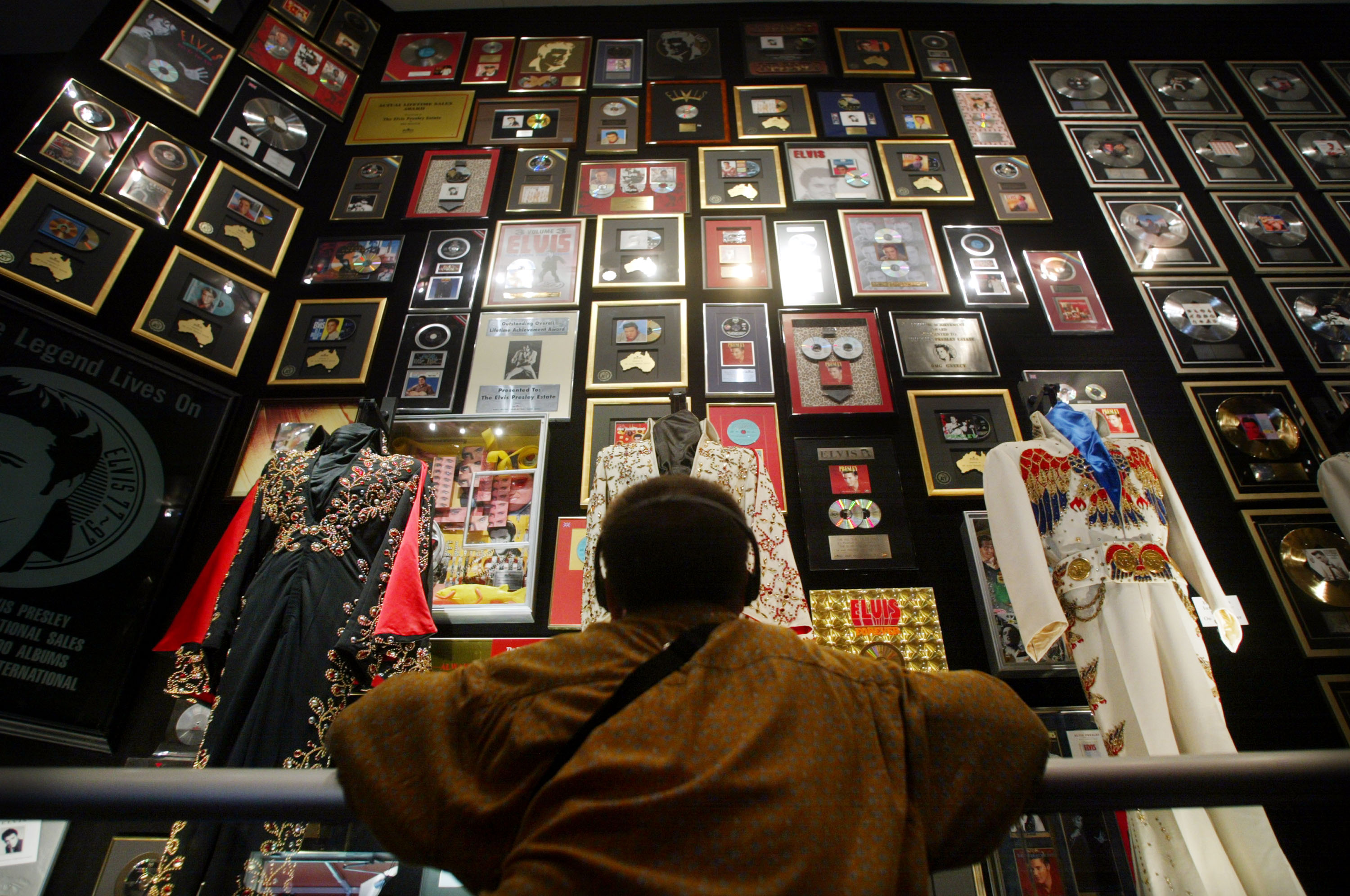 MEMPHIS, TN - AUGUST 12:  An Elvis fan views Presley memorabilia in the racquetball building at Graceland during Elvis Week on August 12, 2002 in Memphis, Tennessee.  75,000 fans are expected to attend the celebration of all things Elvis which this year marks the 25th anniversary of Presley