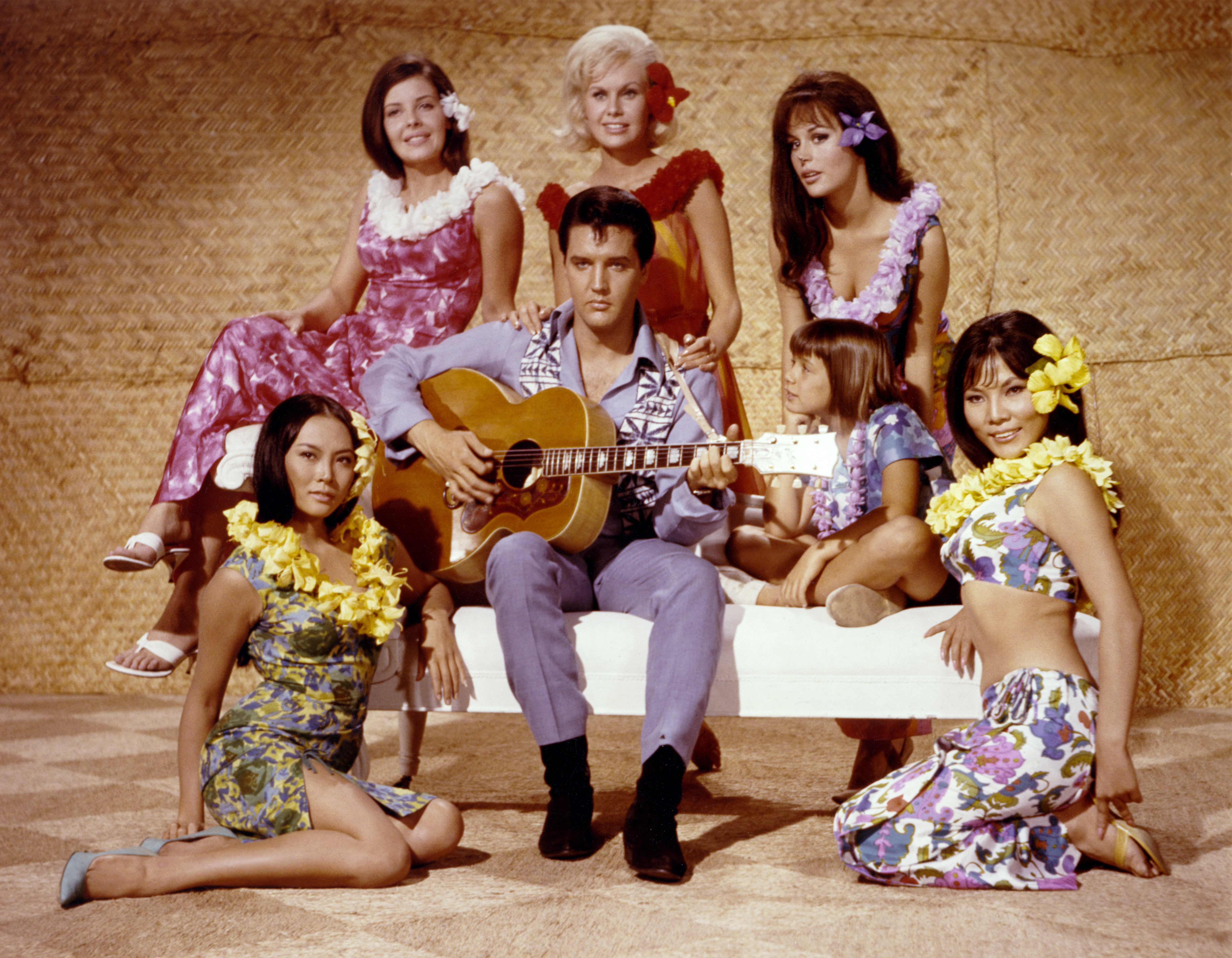American singer and actor Elvis Presley surrounded by Korean actress Linda Wong, American Julie Parrish, British Suzanna Leigh, American Marianna Hill, American Donna Butterworth (little girl), and Chinese Irene Tsu, on the set of Paradise, Hawaiian Style directed by Canadian Michael D. Moore. (Photo by Sunset Boulevard/Corbis via Getty Images)