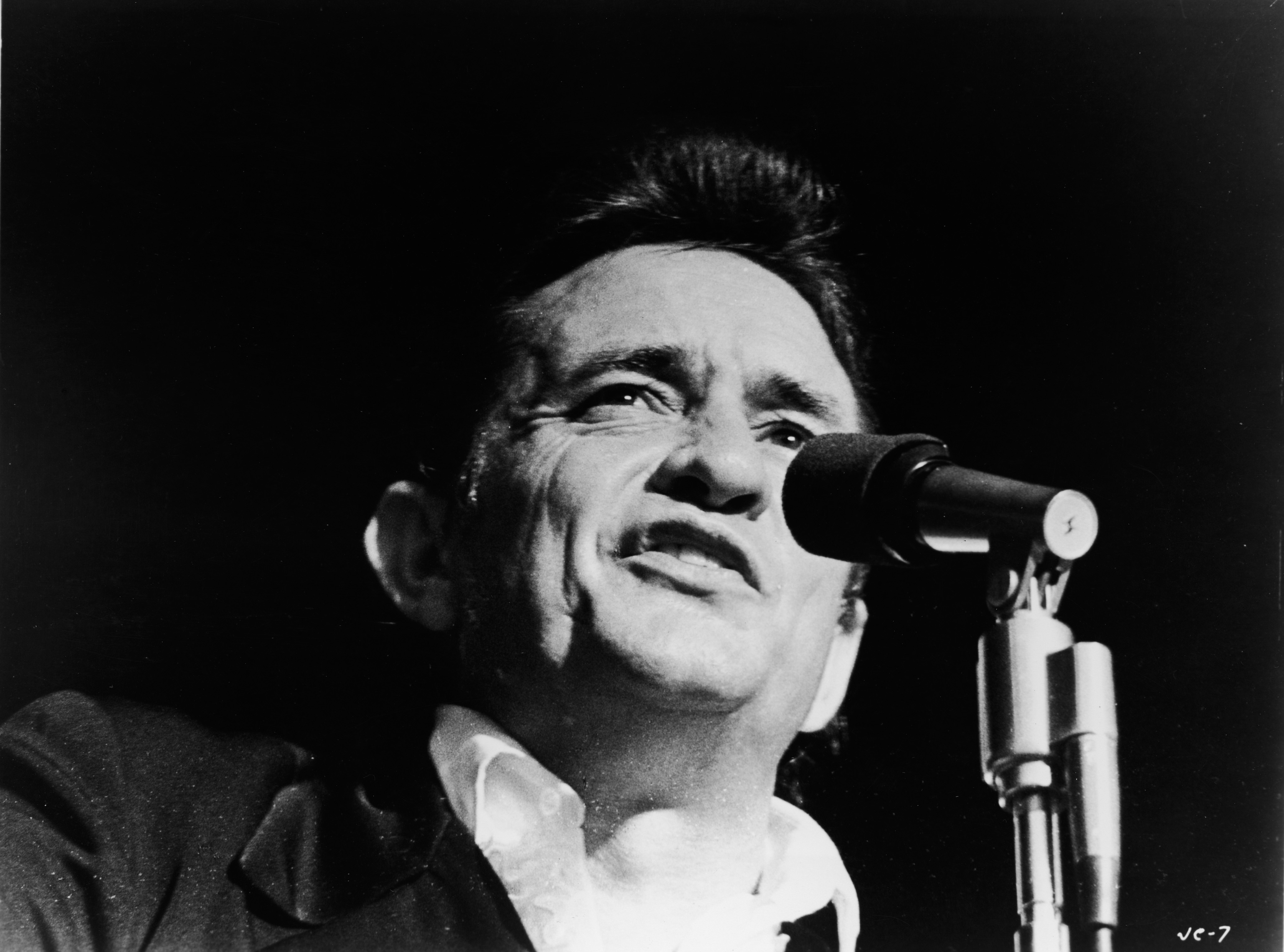 Headshot of American country singer Johnny Cash (1932 - 2003) singing on stage in a still from the film,