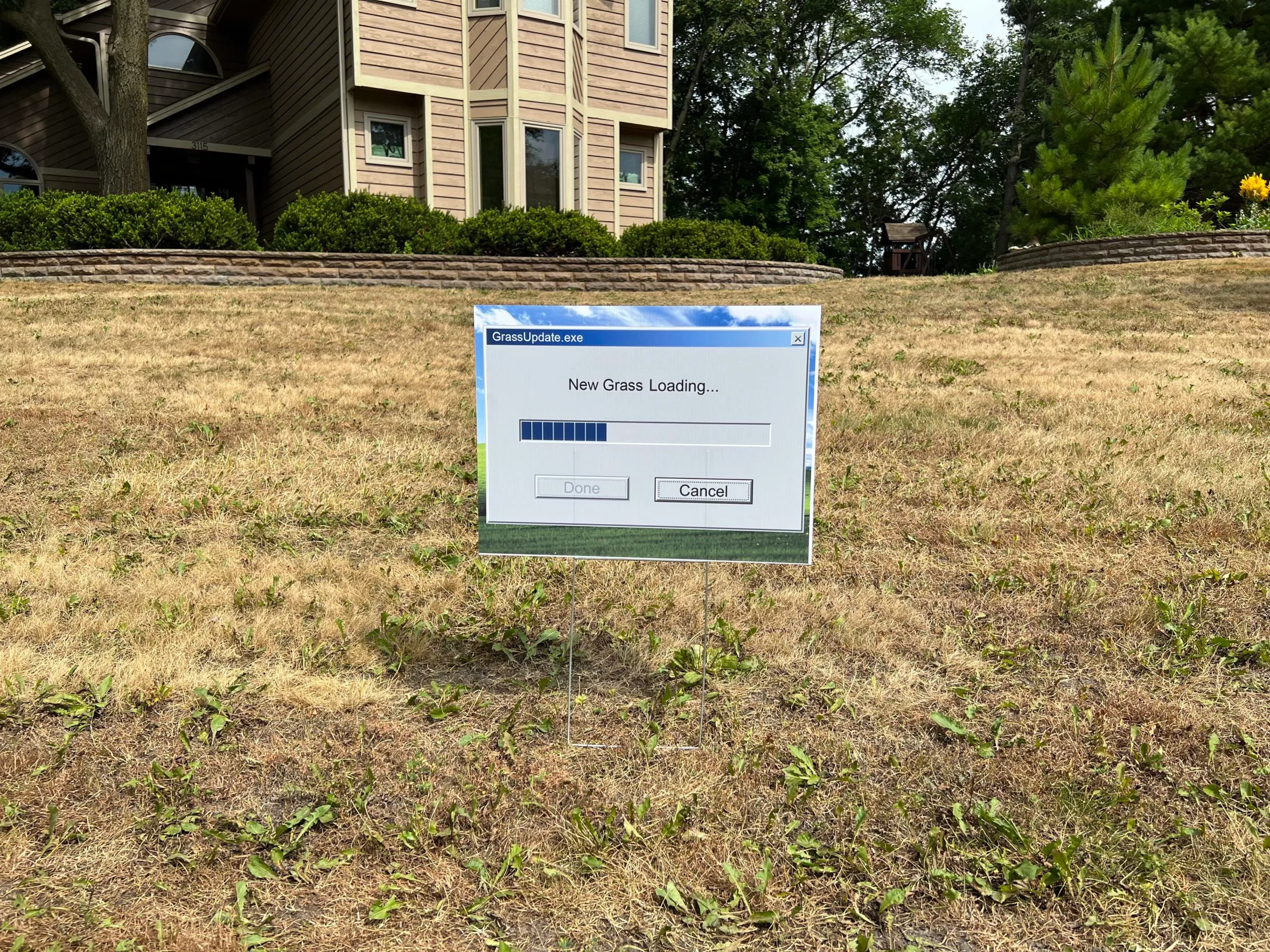 lawn full of dead grass with sign reading new grass loading