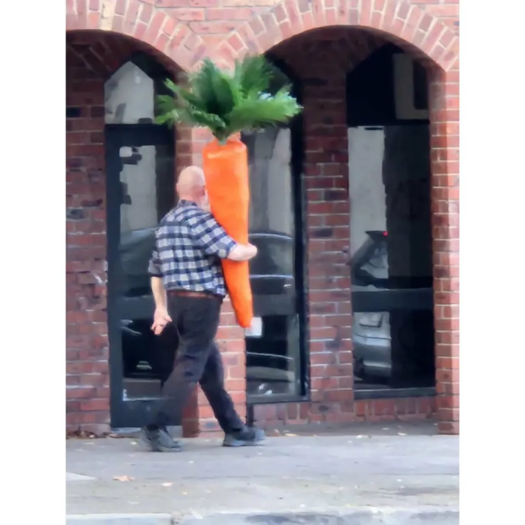 a man holding a carrot while walking down the street