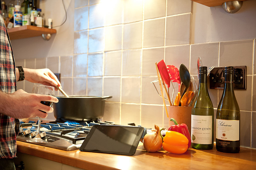 A man using an Apple iPad Mini tablet computer in a kitchen setting-162792832 A man using an Apple iPad Mini tablet computer in a kitchen setting-162792832