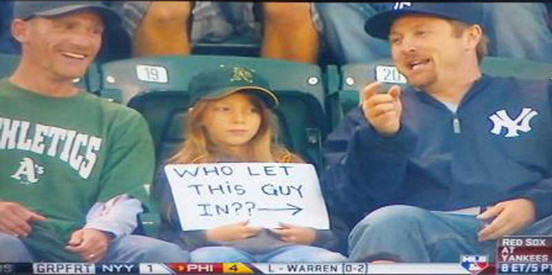 oakland a's fan young oakland a's fan with a sign pointed at a yankees fan