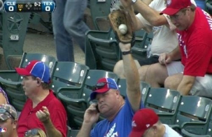fan catching a ball on the phone fan on the phone while catching a foul ball