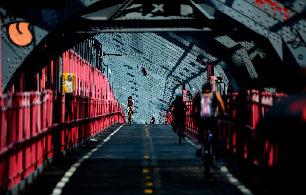 People ride their bicycles over the Williamsburg bridge