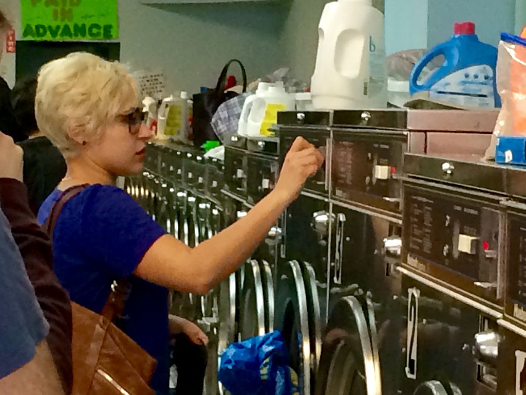 A Woman Using A Coin Operated Washing Machine