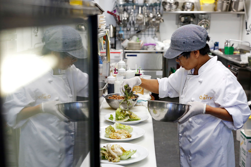 A chef places toppings onto plates of salad