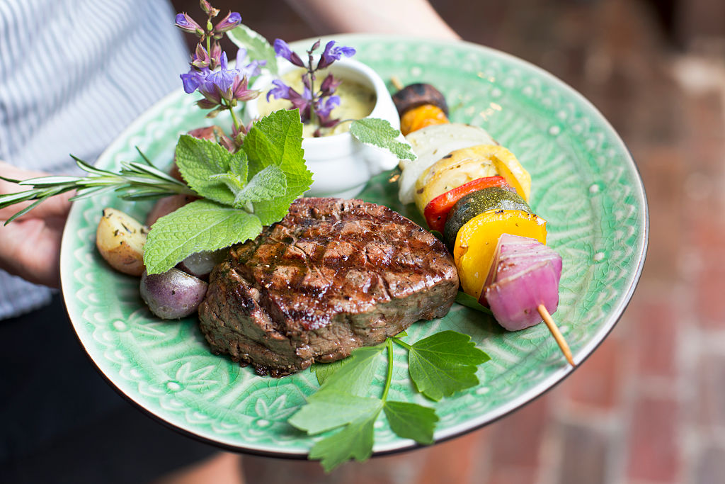 A beautiful steak dish is carried by a waiter