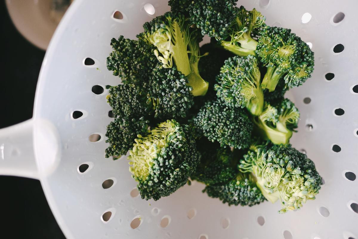 broccoli Person cleans broccoli with a strainer.