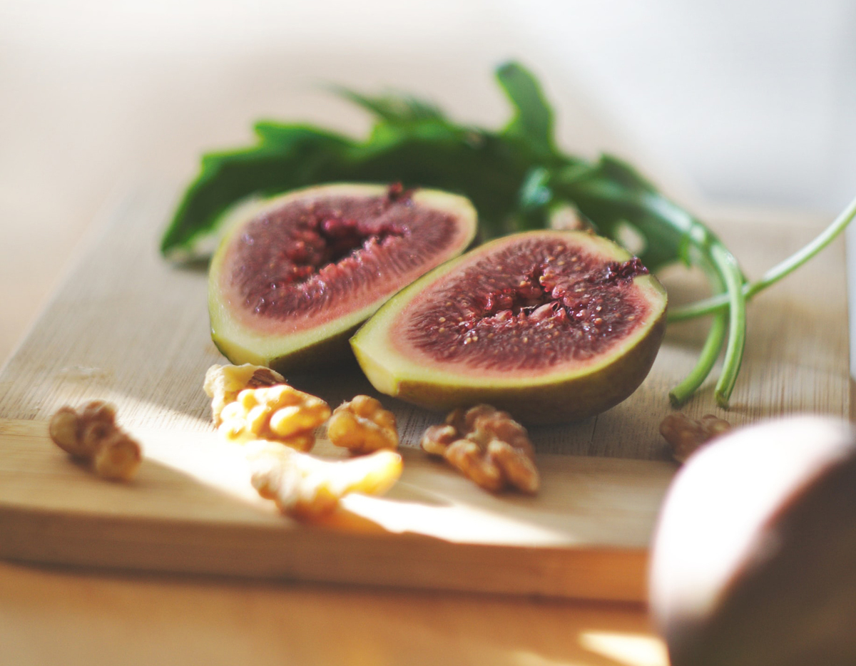inside a fig A cut fig lies on a cutting board with arugula and walnuts.