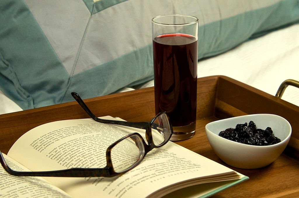 tart cherry juice 453832262 tart cherry juice, a book, glasses, and dried fruit on a bedside tray