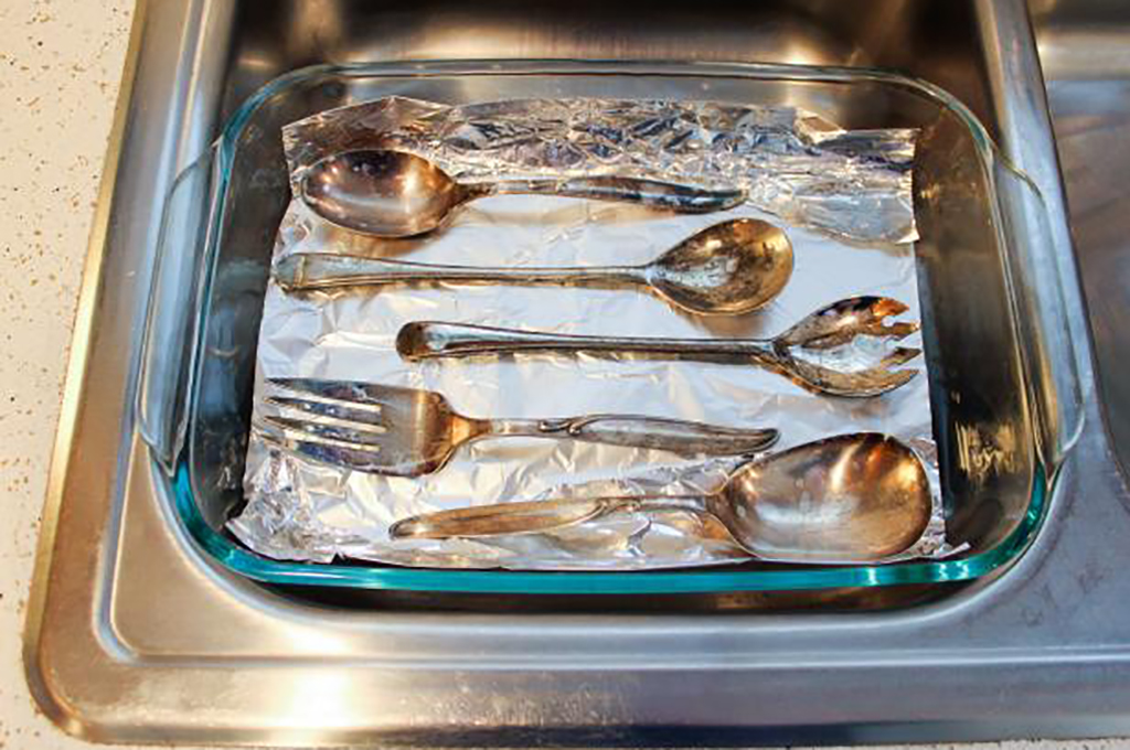 Cleaning silverware Silverware in dish with foil