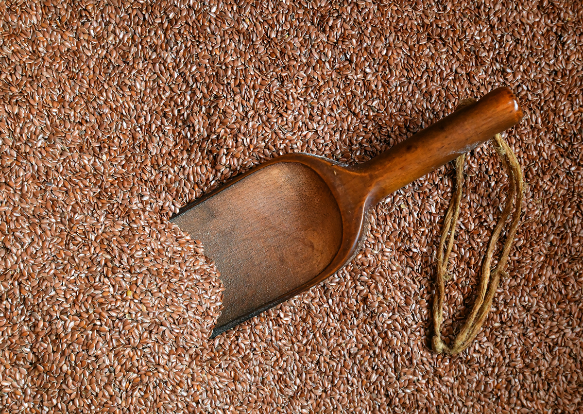 spoon in flaxseeds - 1041788610 A wooden spoon is in a pile of flaxseeds.