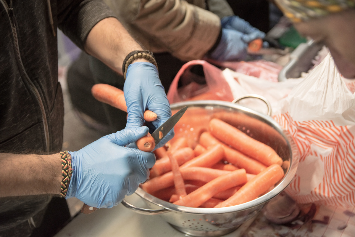 cutting carrots - 1060872252 An activist in Athens cuts carrots to prepare meals for people in need.