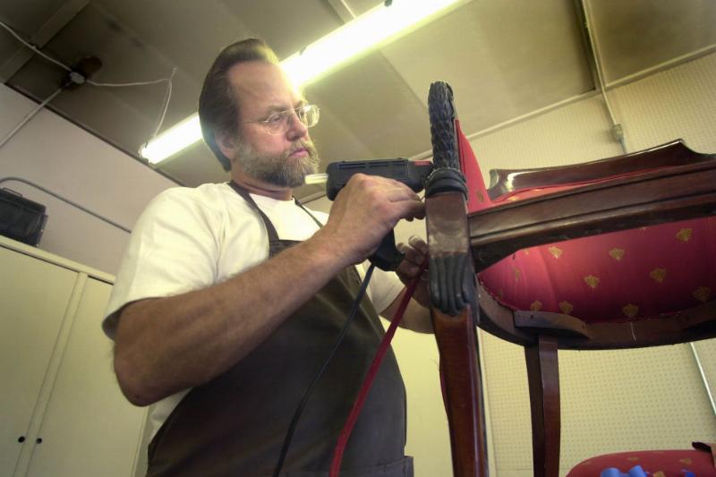 Hot Glue Gun -1095693828 Man using a hot glue gun on a chair
