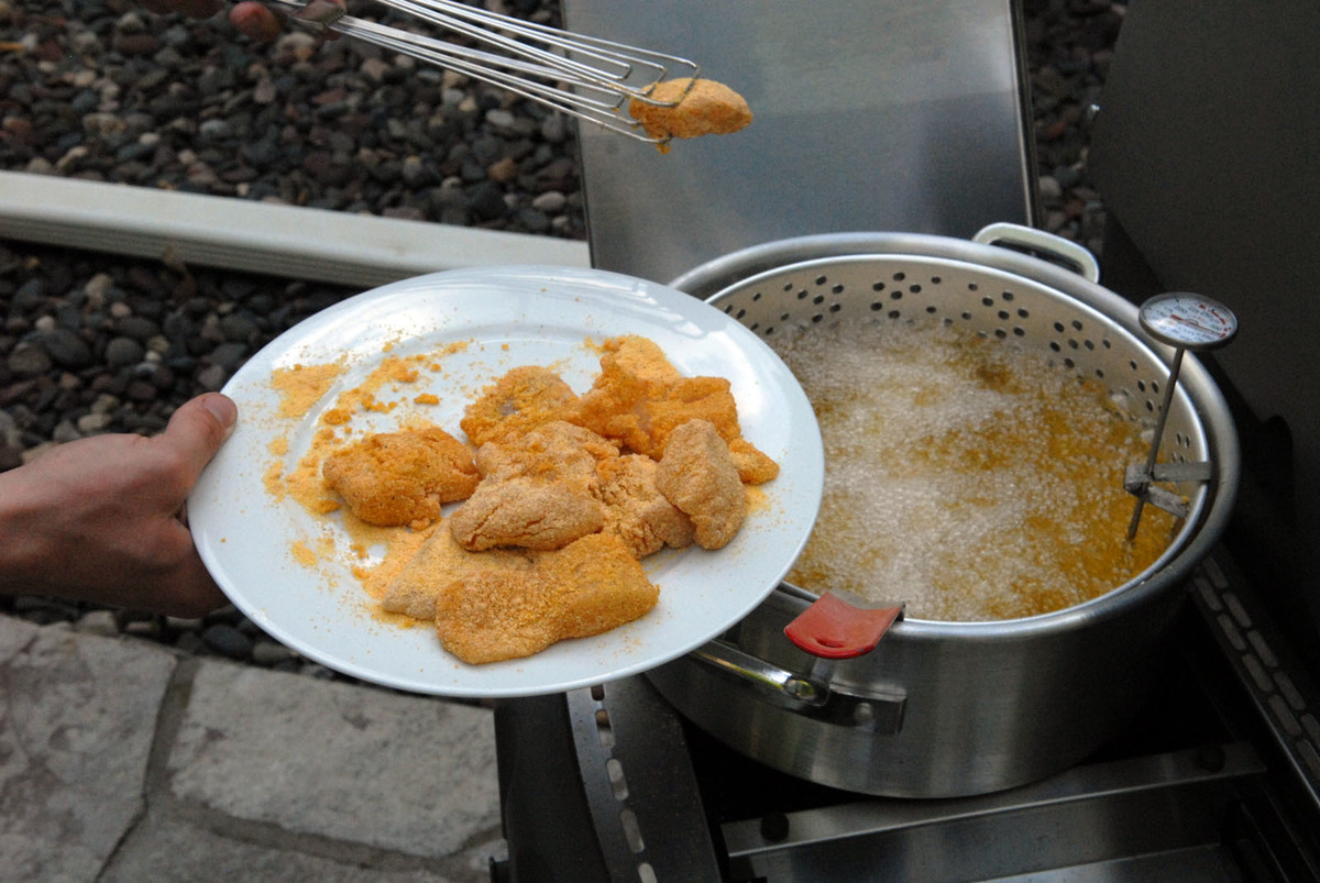 fried fish - 1155697426 A person removes fried fish fillets from a frying pan.