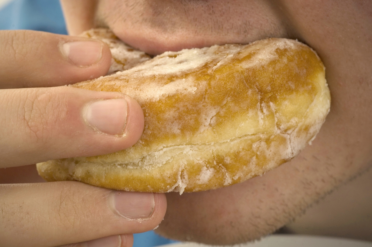 eating a donut - 129378073 Close-up of man eating jam donut.