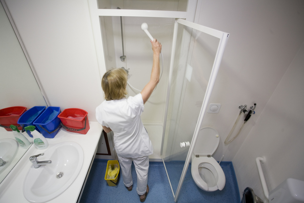 cleaning a shower - 151060865 A worker cleans the shower at the Maternity of Saint Vincent De Paul Hospital.