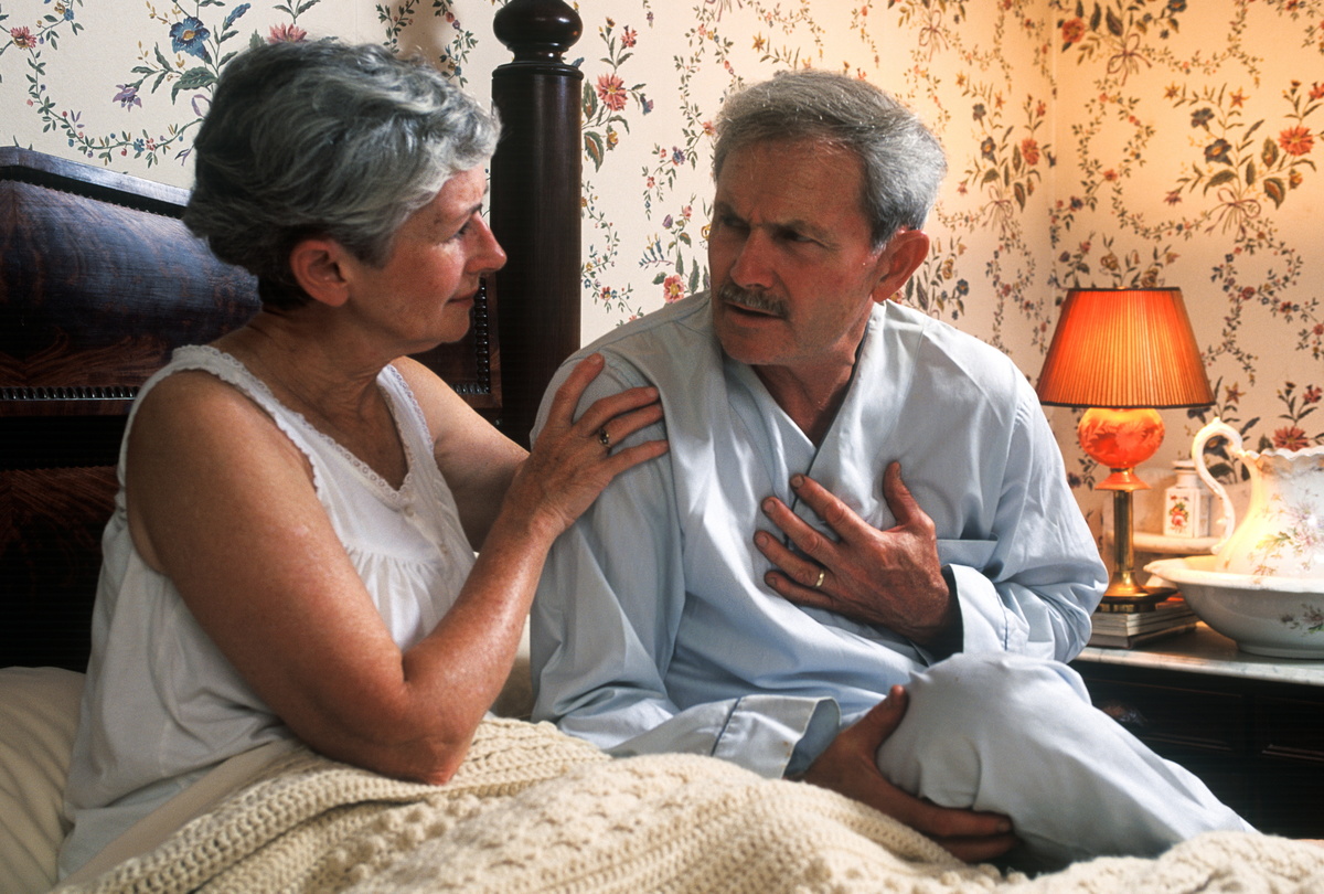 heartburn - 453028559 Senior man with chest pain is comforted by his concerned wife.