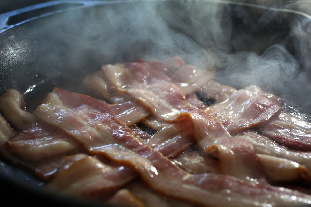 cooking bacon - 494330620 Bacon cooks in a frying pan.