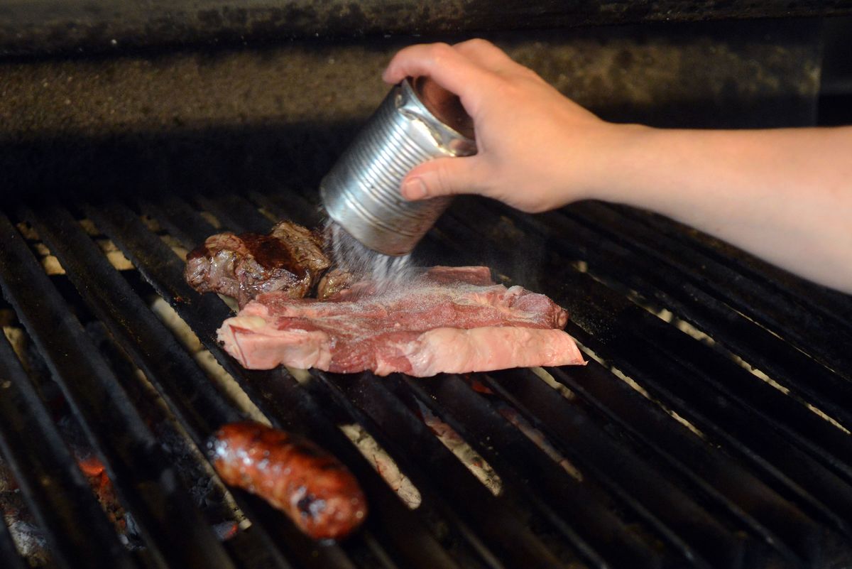 grilling red meat - 494517620 A cooker puts salt on beef in a traditional grill restaurant.