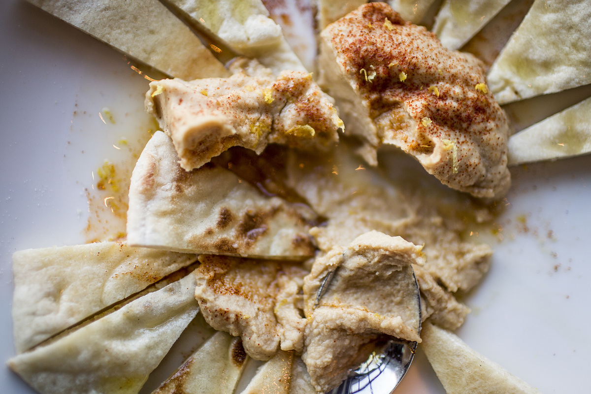 hummus dip - 507319584 Pita and bread are dipped into a pile of hummus.