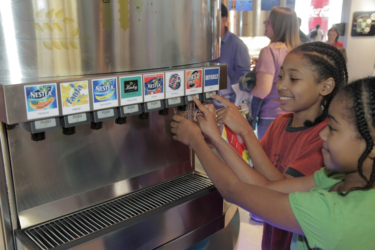 pouring soda - 635745044 Two girls pour soda at the 'Taste It!' exhibit in the World of Coca-Cola.