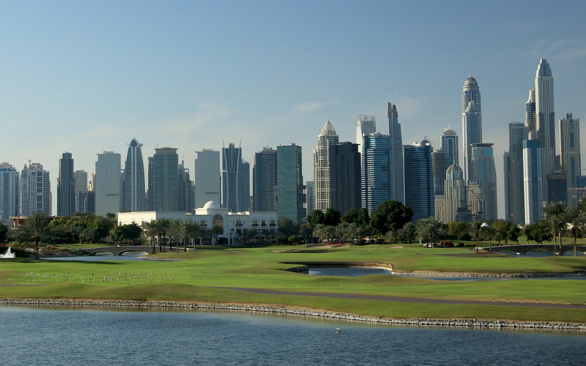 Dubai golf - 644874048 View of the 18th hold at The Adress Montgomerie Golf Club features the city of Dubai in the background.
