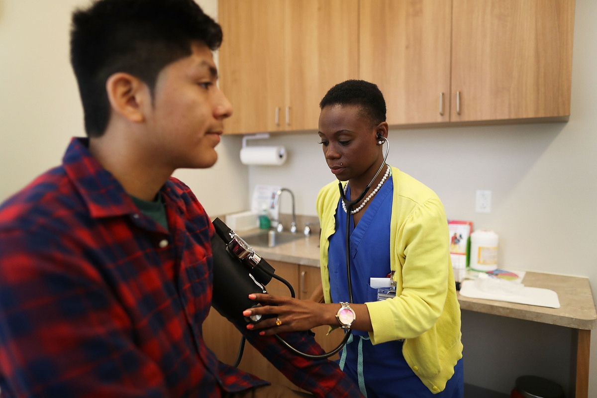 checking blood pressure - 682338818 Man has his blood pressure measured by Linda Williams, a medical assistant.