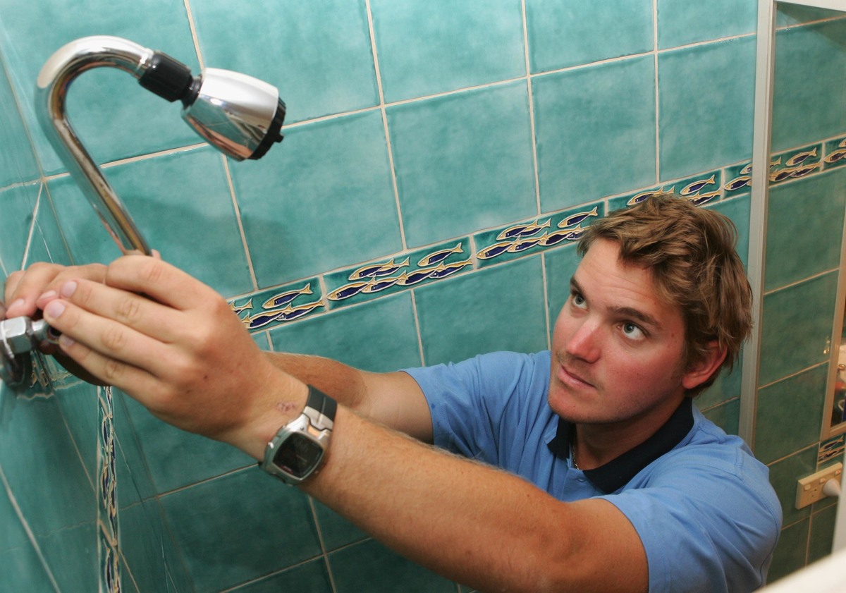 installing a showerhead - 73849114 A tradesman intalls a water saving showerhead.