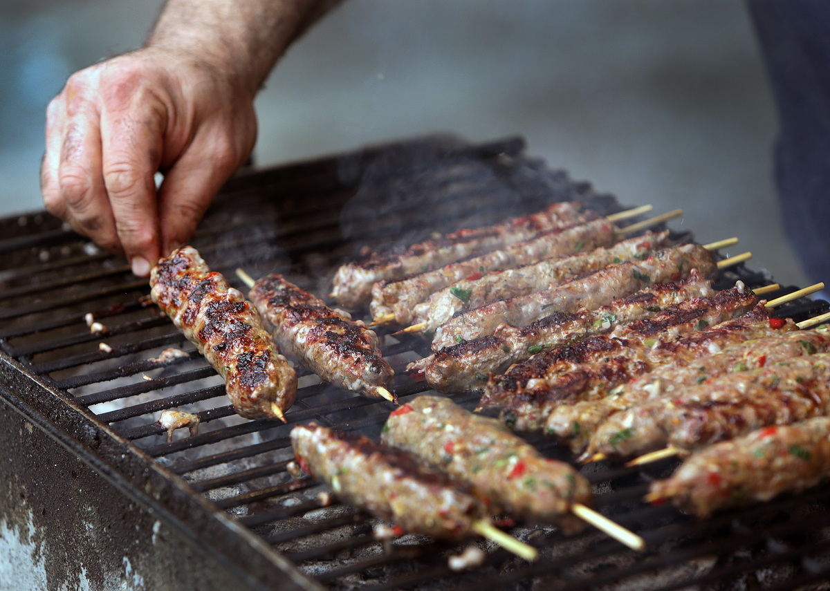 BBQ - 802624736 Man grills lamb kebabs.
