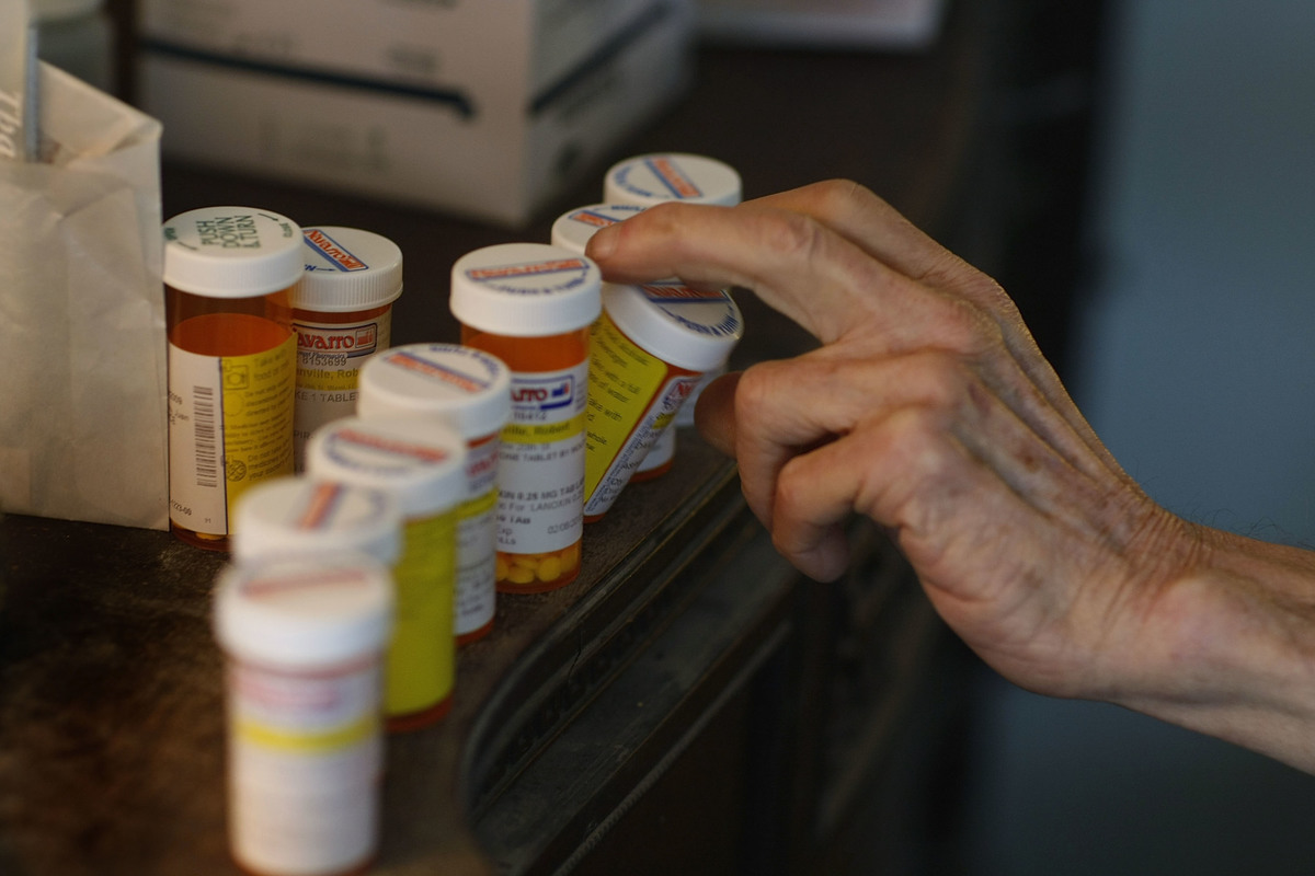 pill bottles - 85095812 Robert Granville reaches for a medicine bottle as he takes his prescription pills.