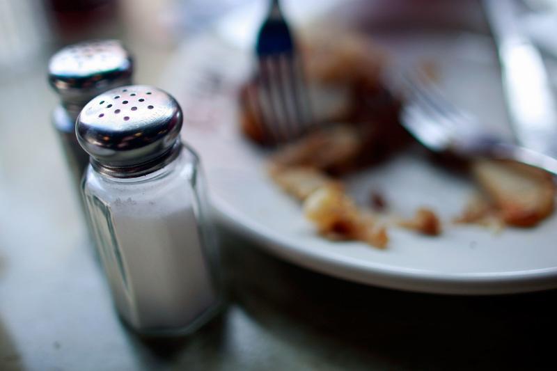 salt shaker - 86182526 Salt and pepper shakers sit near a plate of food at a diner.