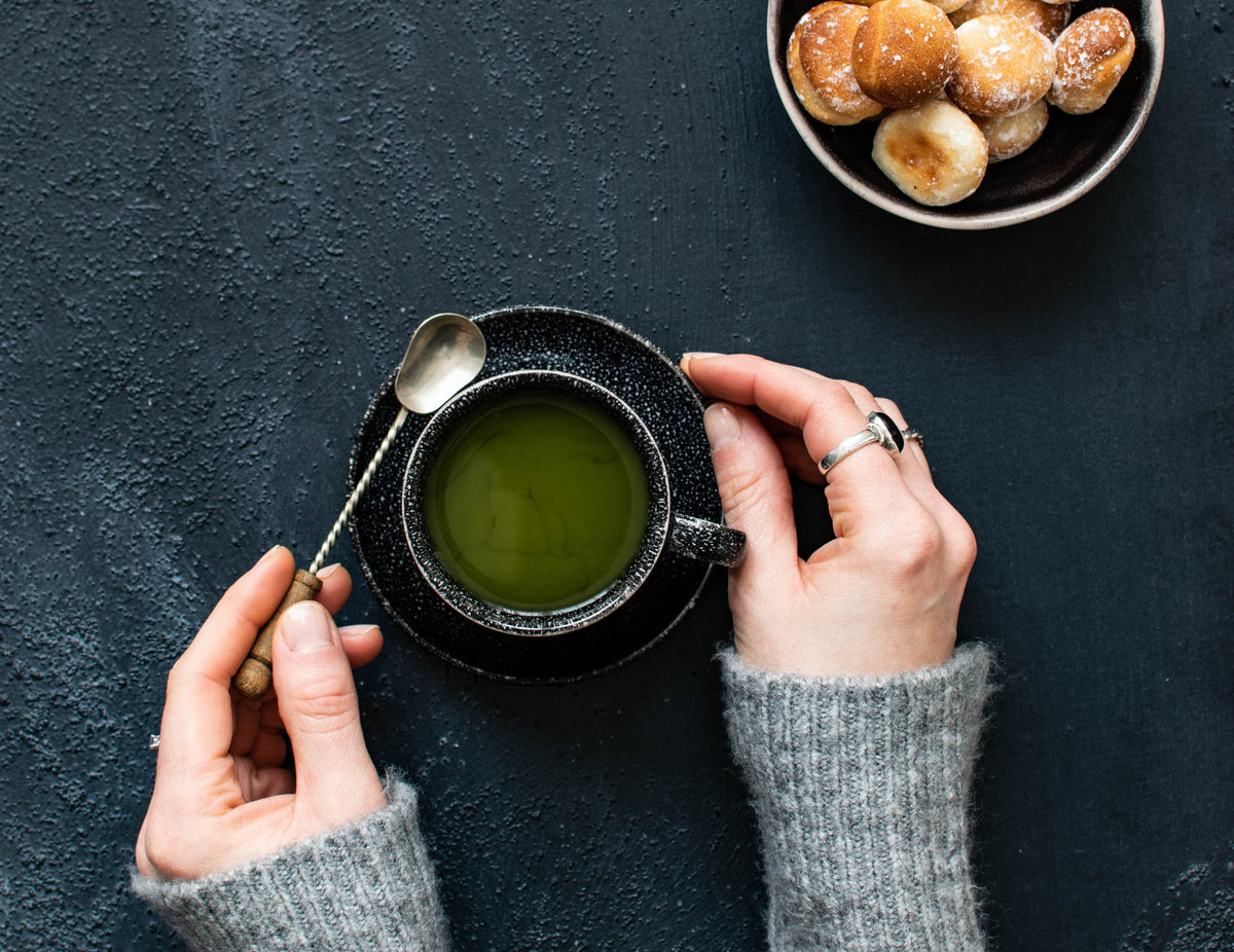 green tea A woman lifts a spoon out of a cup of green tea.