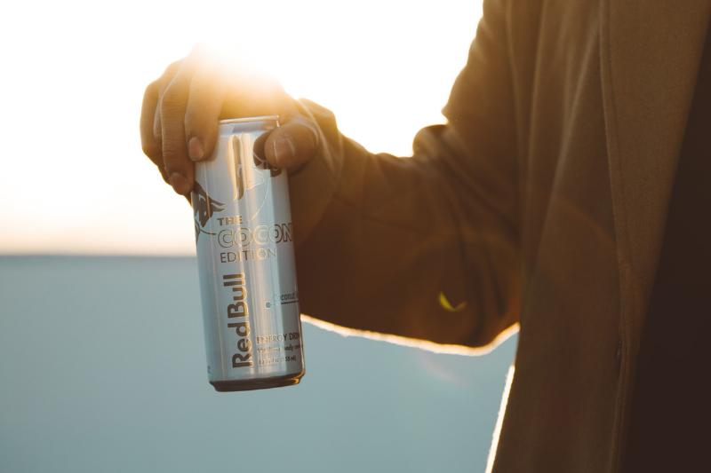 holding redbull A man holds a can of Red Bull against the sunlight.