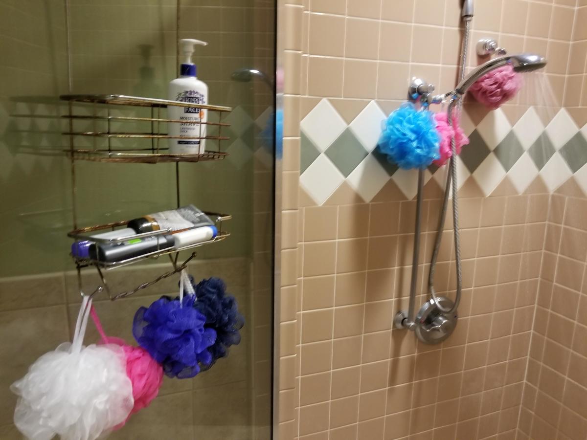 many colored loofahs Multiple colored loofahs hang from a shower caddy and showerhead.