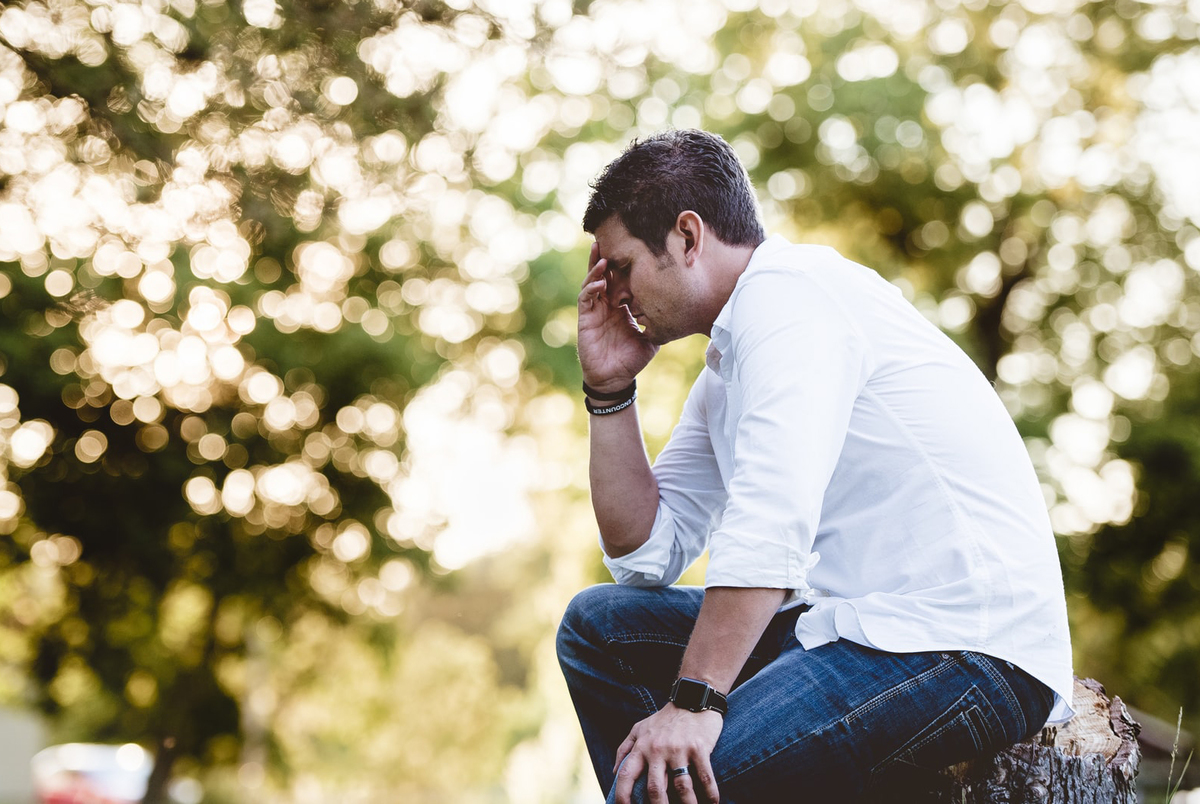 sad man thinking Stressed man contemplates his existence in front of bright lights.