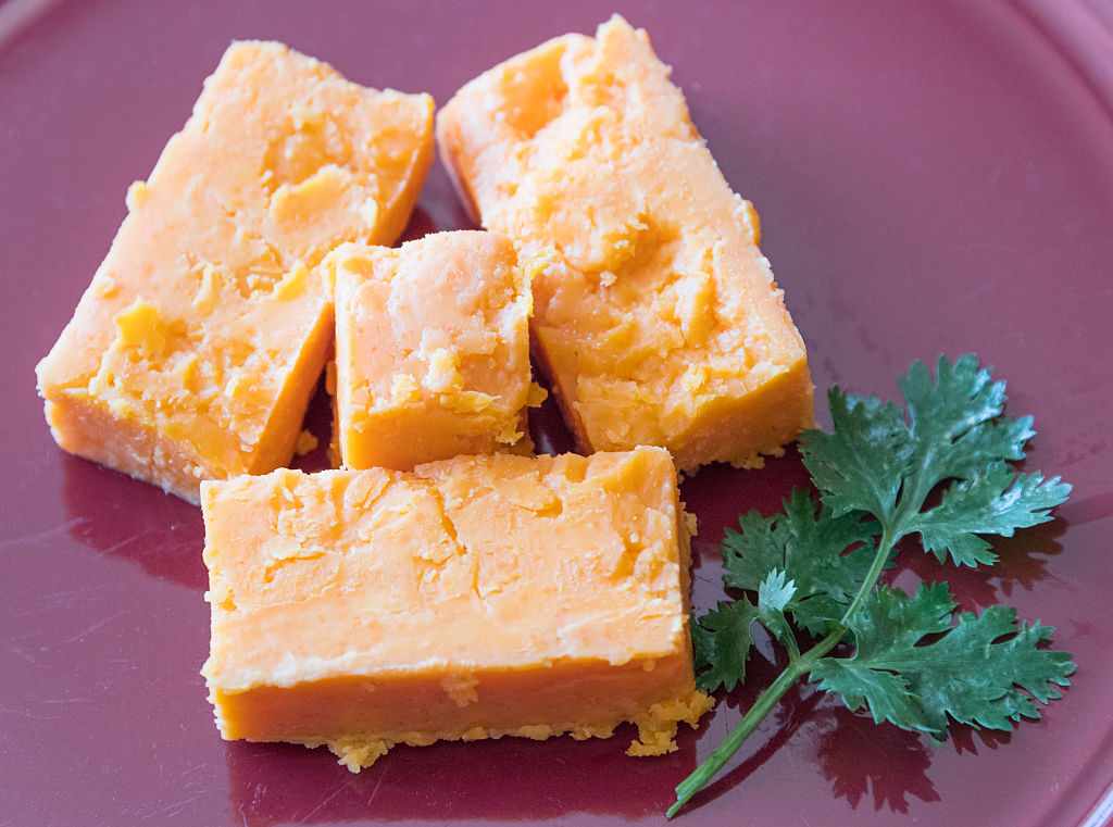 cheese 588670072 four pieces of hard ripened cheese garnished with cilantro leaves