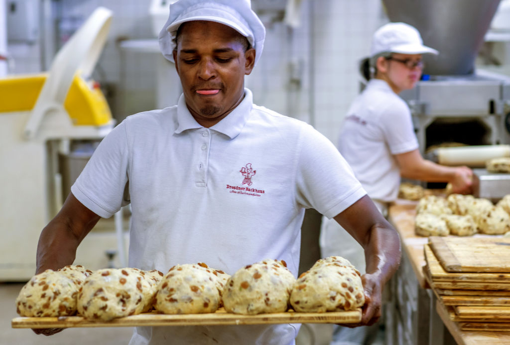 gluten 1178895602 a baker holding five things of dough about to go in the oven