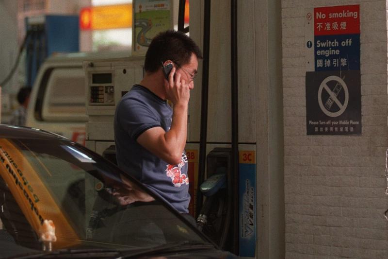 Driver using mobile phone Man on the phone at a gas station