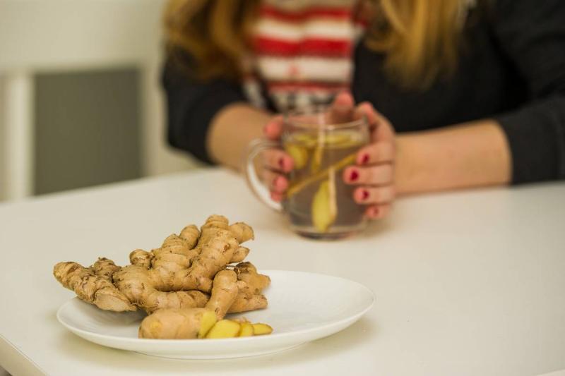 ginger tea - 1038949554 A woman makes ginger tea with fresh ginger laid out on the table.