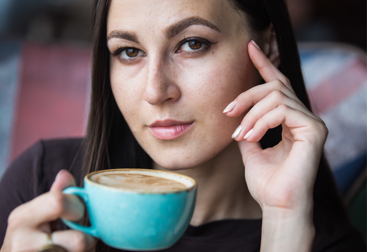 drinking coffee - 1152304146 A woman drinks coffee from a blue mug.
