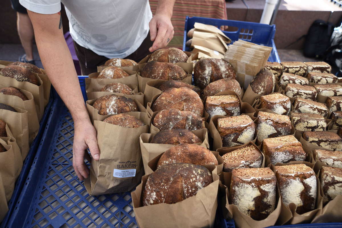 whole grain bread - 1179437409 A bakery worker arranges a display of artisan bread.