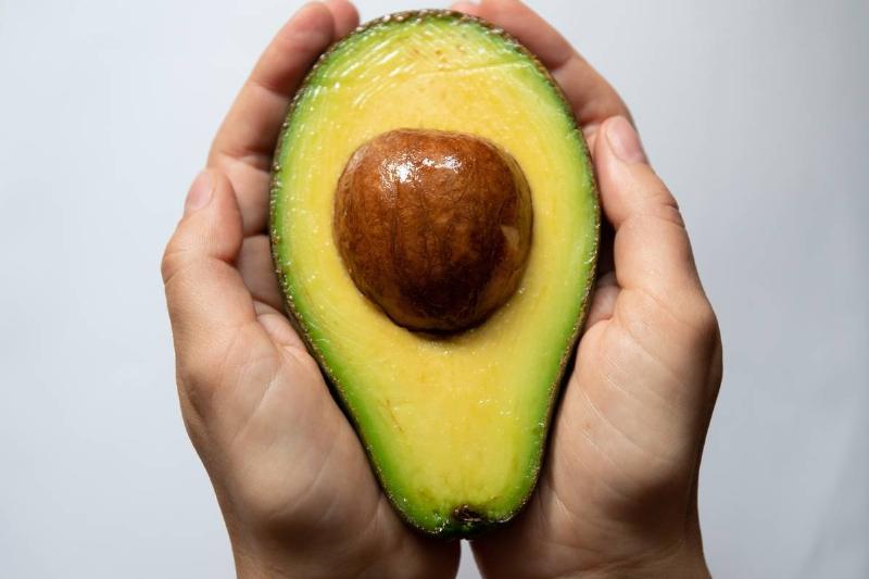 holding avocado - 1183618147 A person holds an avocado half.