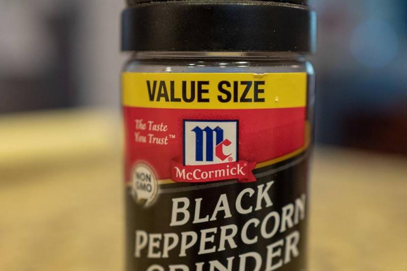black pepper shaker - 1190008475 A plastic shaker is filled with black peppercorns.