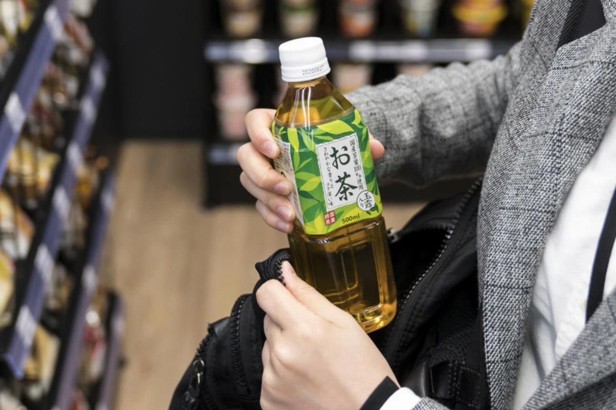 green tea - 1209209867 A woman buys a bottle of iced green tea in a Japanese convenient store.
