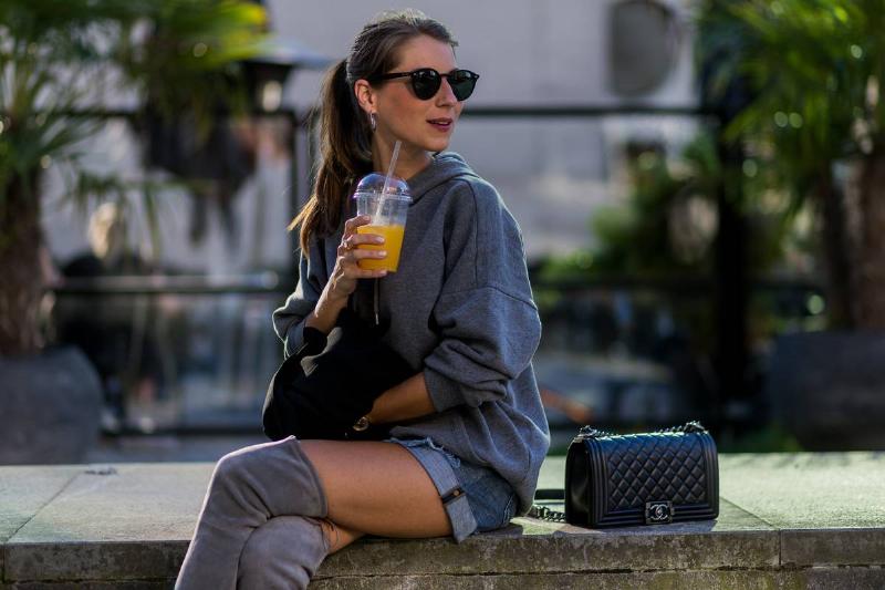 drinking orange juice - 596248526 A woman drinks orange juice outside.
