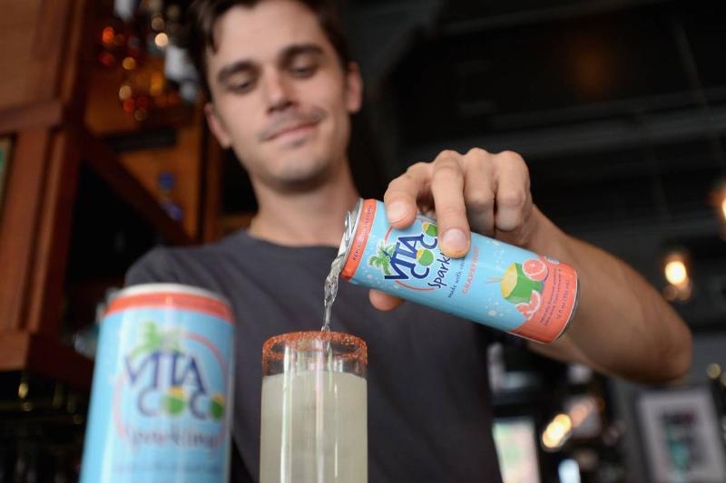 sparkling water-982903694 A man pours a sparkling drink with grapefruit and carbonated coconut water into a glass.