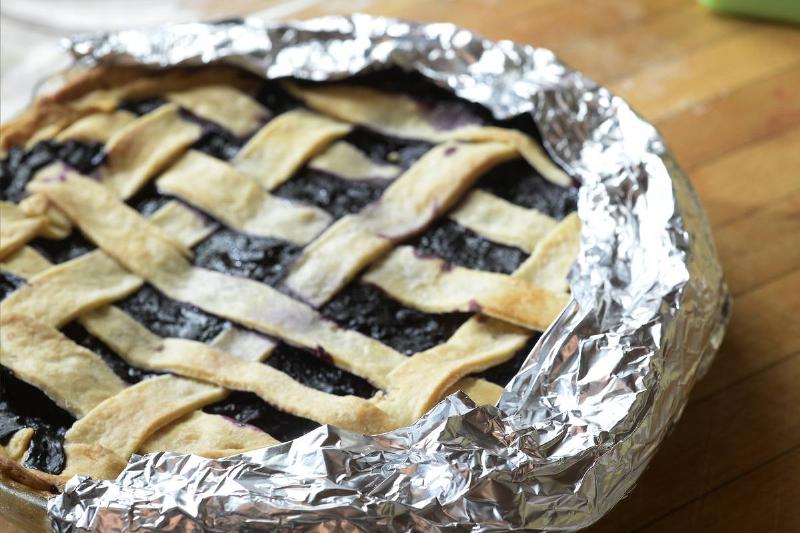Aluminum foil is wrapped around a pie crust.
