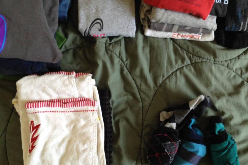 Clothes are folded on a bed.